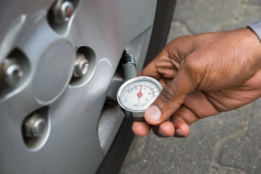 Close-up Of Person Hand Holding Pressure Gauge For Measuring Car Tyre Pressure